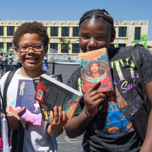 Two children holding up books they got at an OLC book event