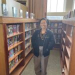 Jaelyn stands between two library bookshelves