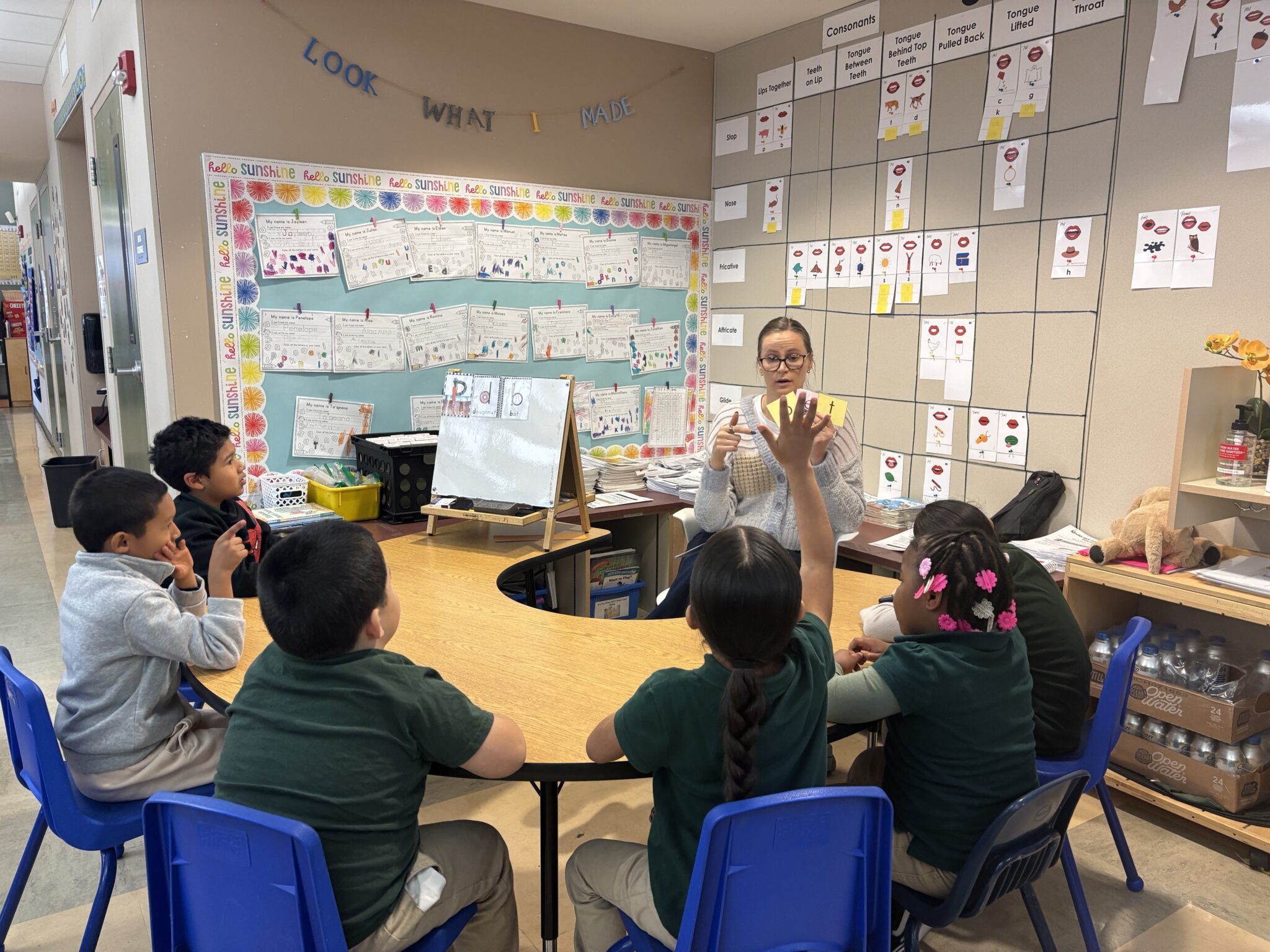 one woman teaching a group of children at a table in a classroom